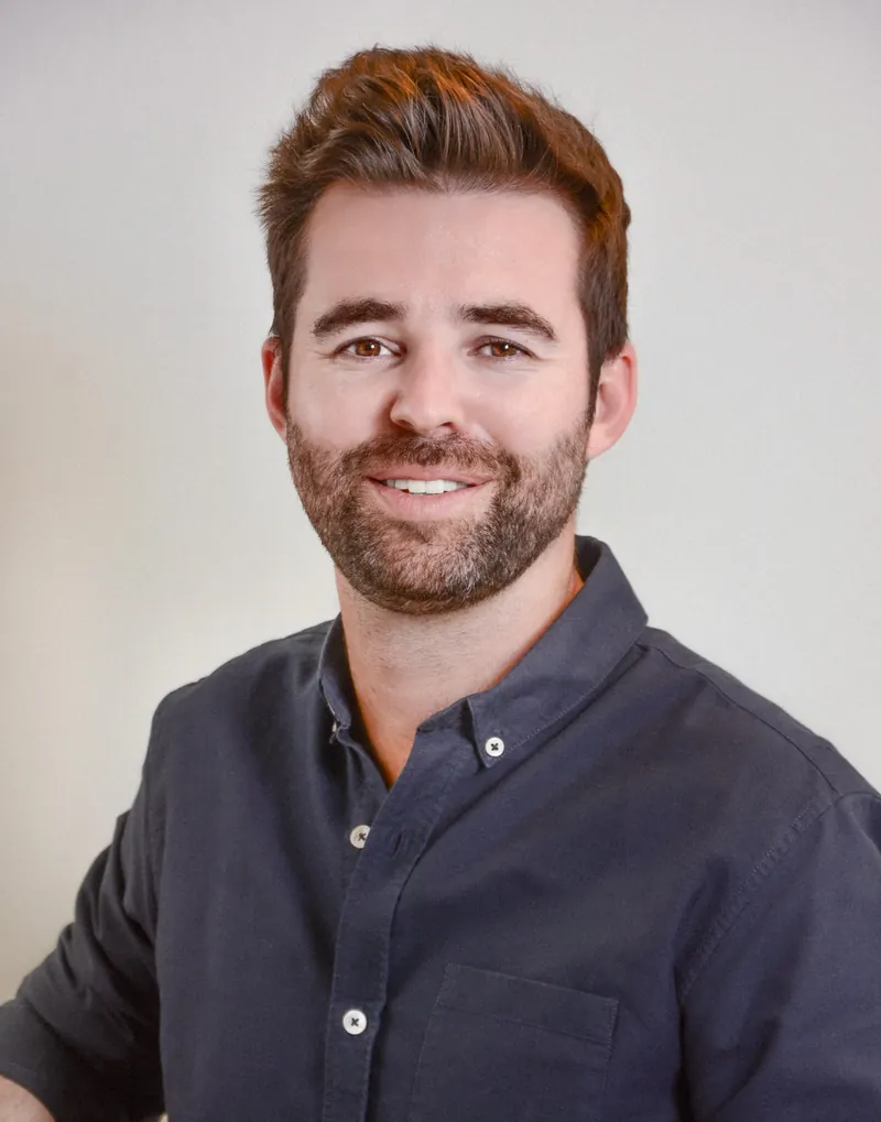 Portrait corporate d’un homme barbu en chemise bleu foncé sur fond clair