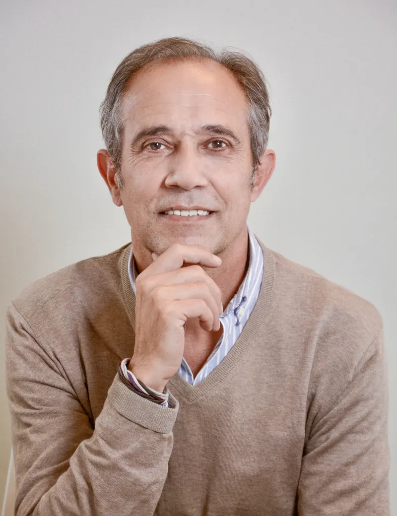 Portrait corporate d'un homme en pull beige, la main sous le menton, sur fond clair