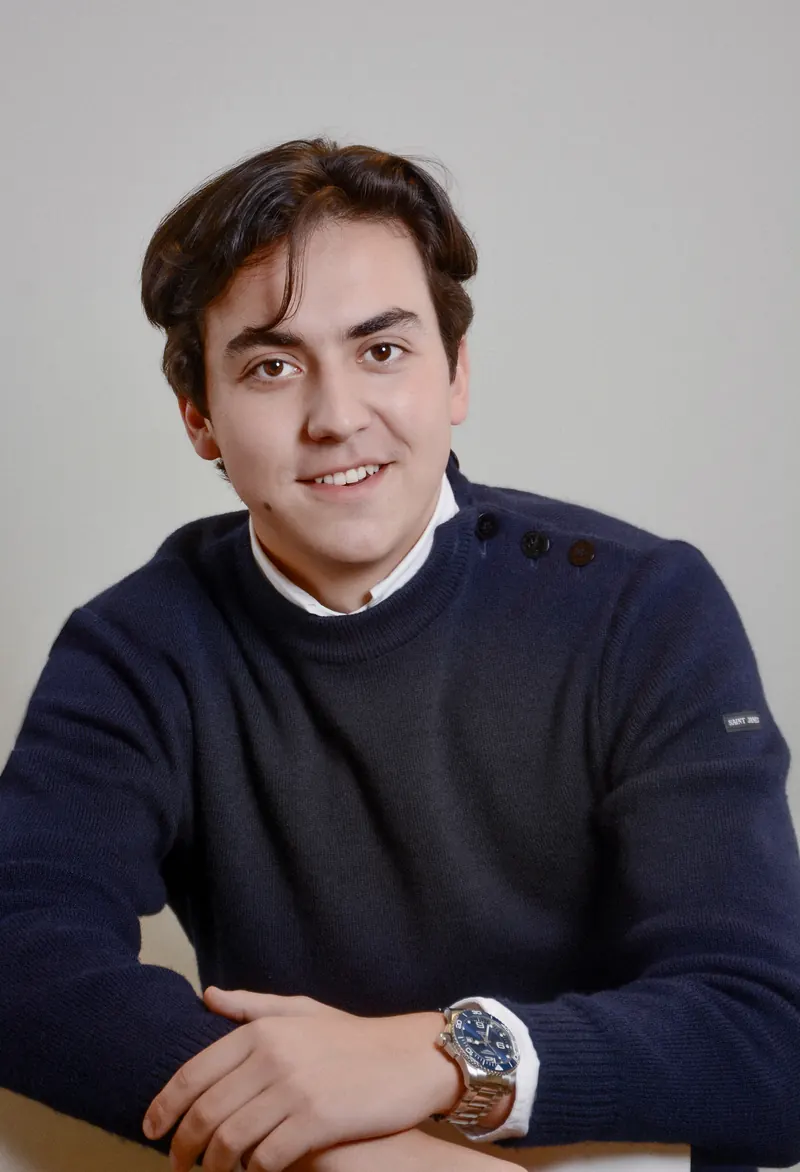 Portrait corporate d'un homme en pull bleu marine, assis, sur fond clair