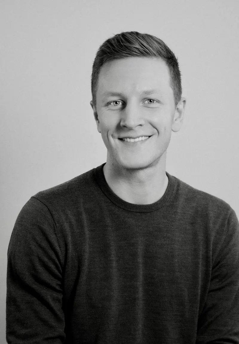 Portrait corporate en noir et blanc d'un homme souriant en pull sombre