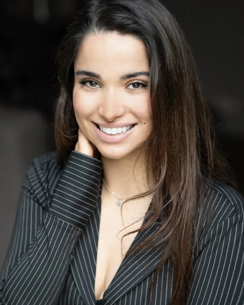 Portrait corporate d'une jeune femme en veste rayée sombre, souriante face à l'objectif