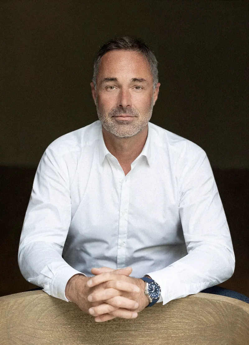Portrait professionnel d’un homme en chemise blanche, assis les mains jointes