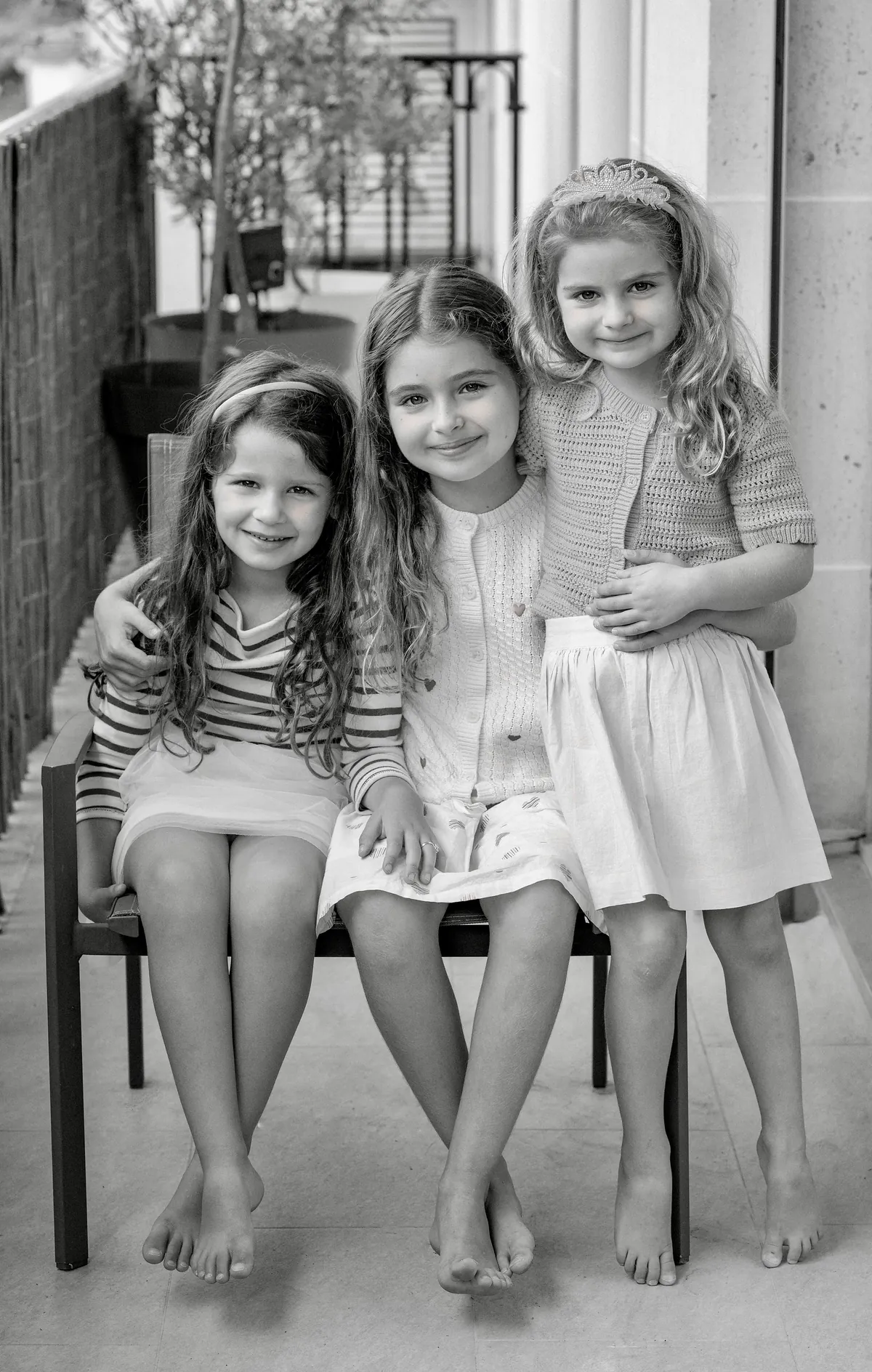 Portrait en noir et blanc de trois jeunes filles réunies pendant une séance photo de famille