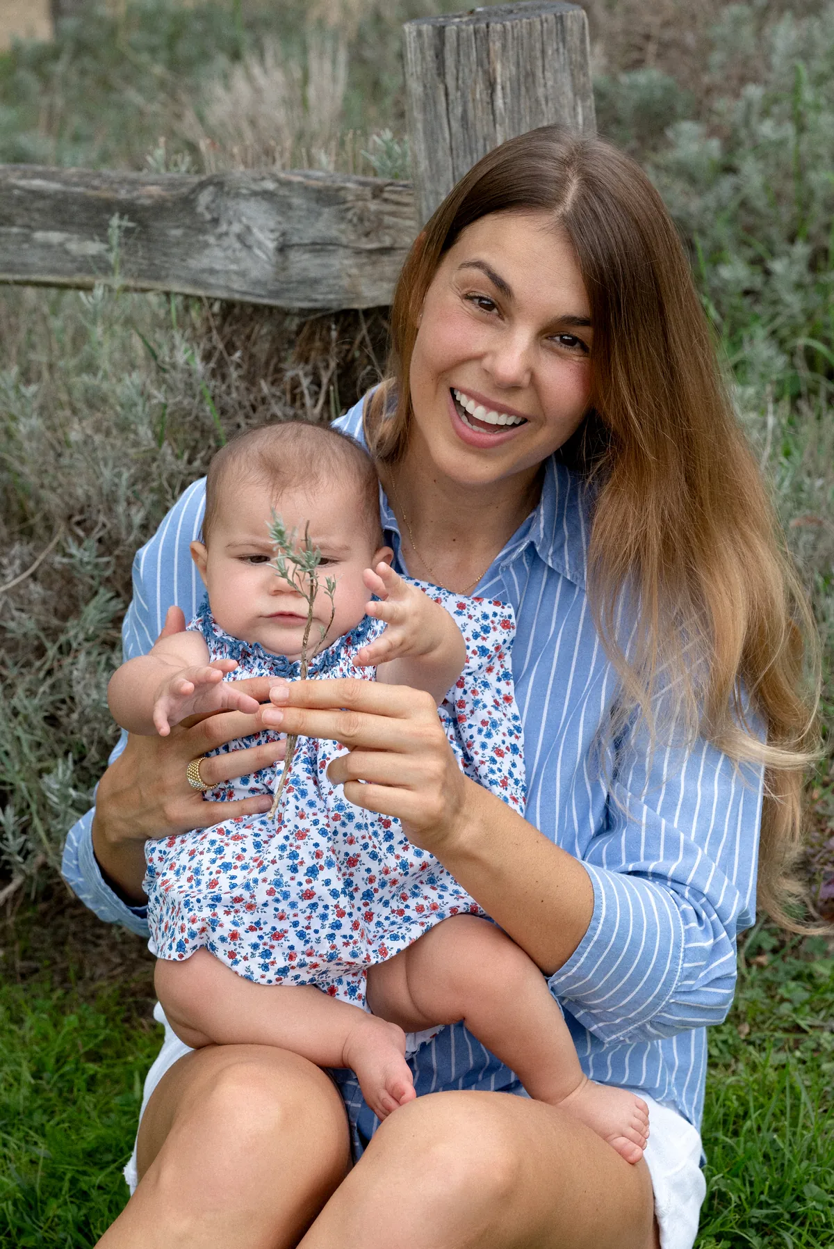 Une mère souriante tenant son bébé pendant une séance photo de famille en extérieur