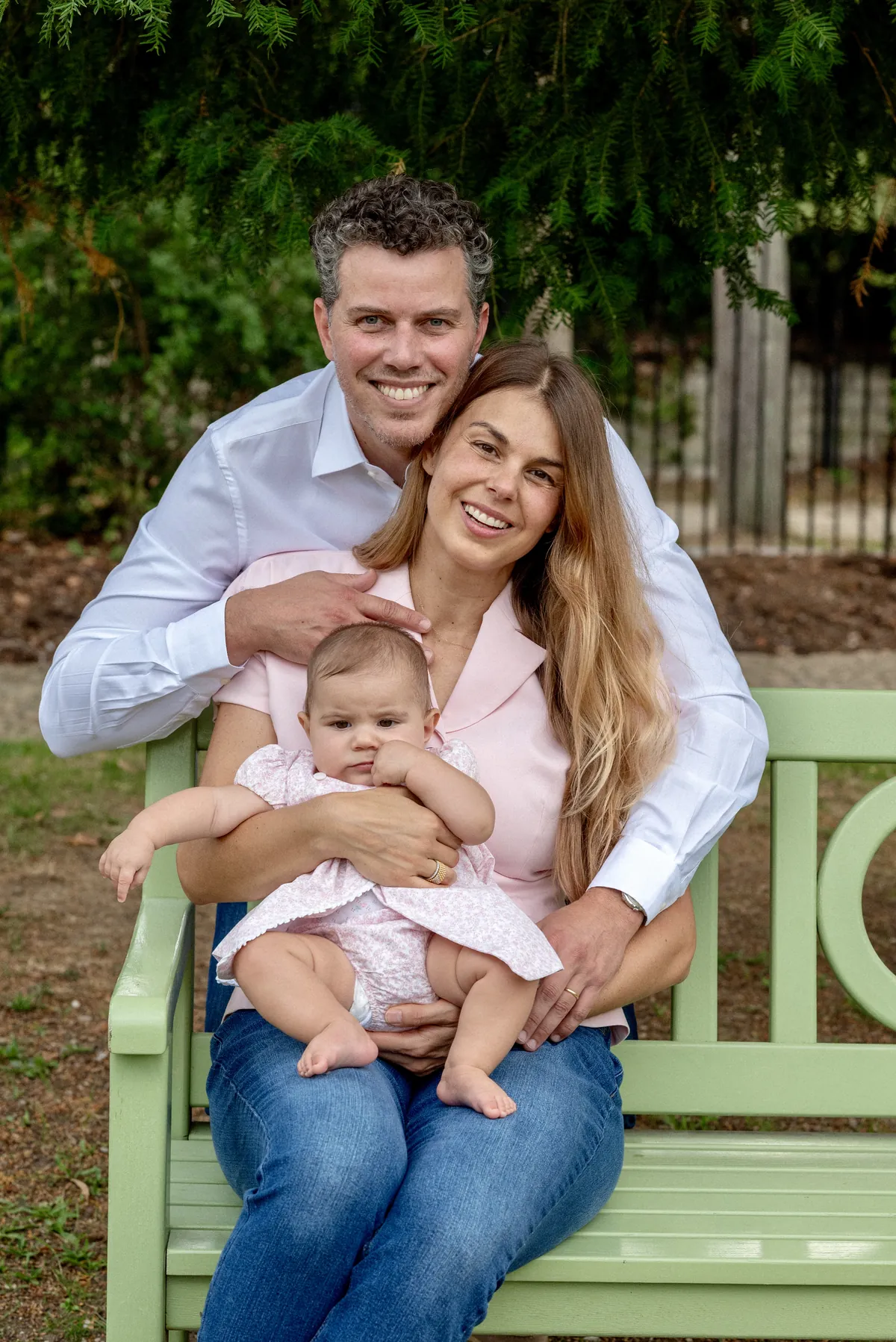 Deux parents assis avec leur bébé sur un banc pendant une séance photo de famille